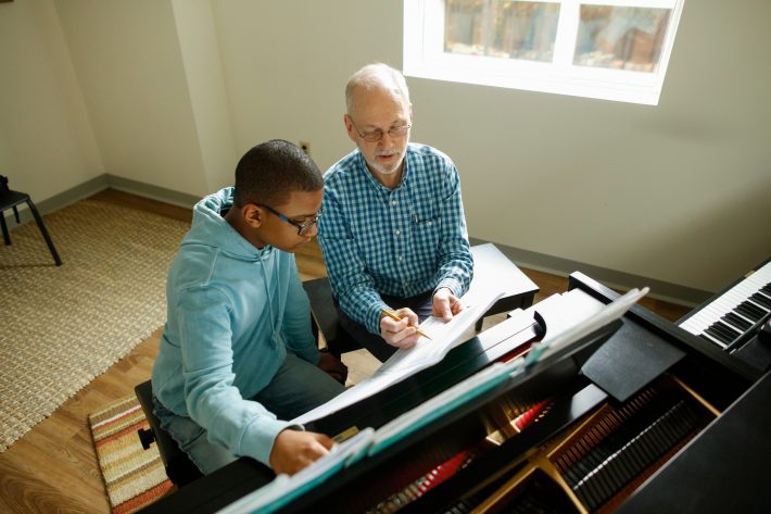 2020_03_03_UR-ADV_HowardSpindler_DoyleyPianoStudentECMS_MW_0250 (1) A Piano teacher points out something in a musical score.