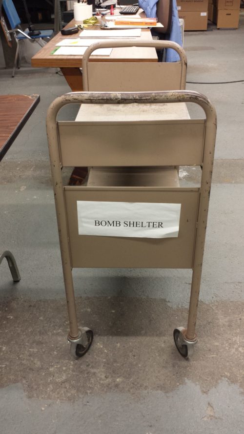 The label designating this book truck as belonging to the BOMB SHELTER was deliberate and distinctive. That the “old” Sibley Music Library basement space had once been designated a civil defense shelter was not lost on members of the working team, and more than one team member routinely answered the basement’s telephone with the greeting, “Bomb Shelter!”.