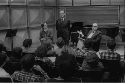 Mr. Schonberg speaking from the stage in Howard Hanson Hall. Professor Donald Shetler of the Music Education Department sits to his left.