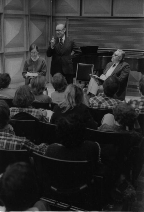 Mr. Schonberg speaking from the stage in Howard Hanson Hall. Professor Donald Shetler of the Music Education Department sits to his left.