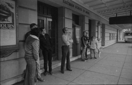 Onlookers outside the Eastman School of Music react as they watch the demolition work in progress on the opposite side of Gibbs Street.
