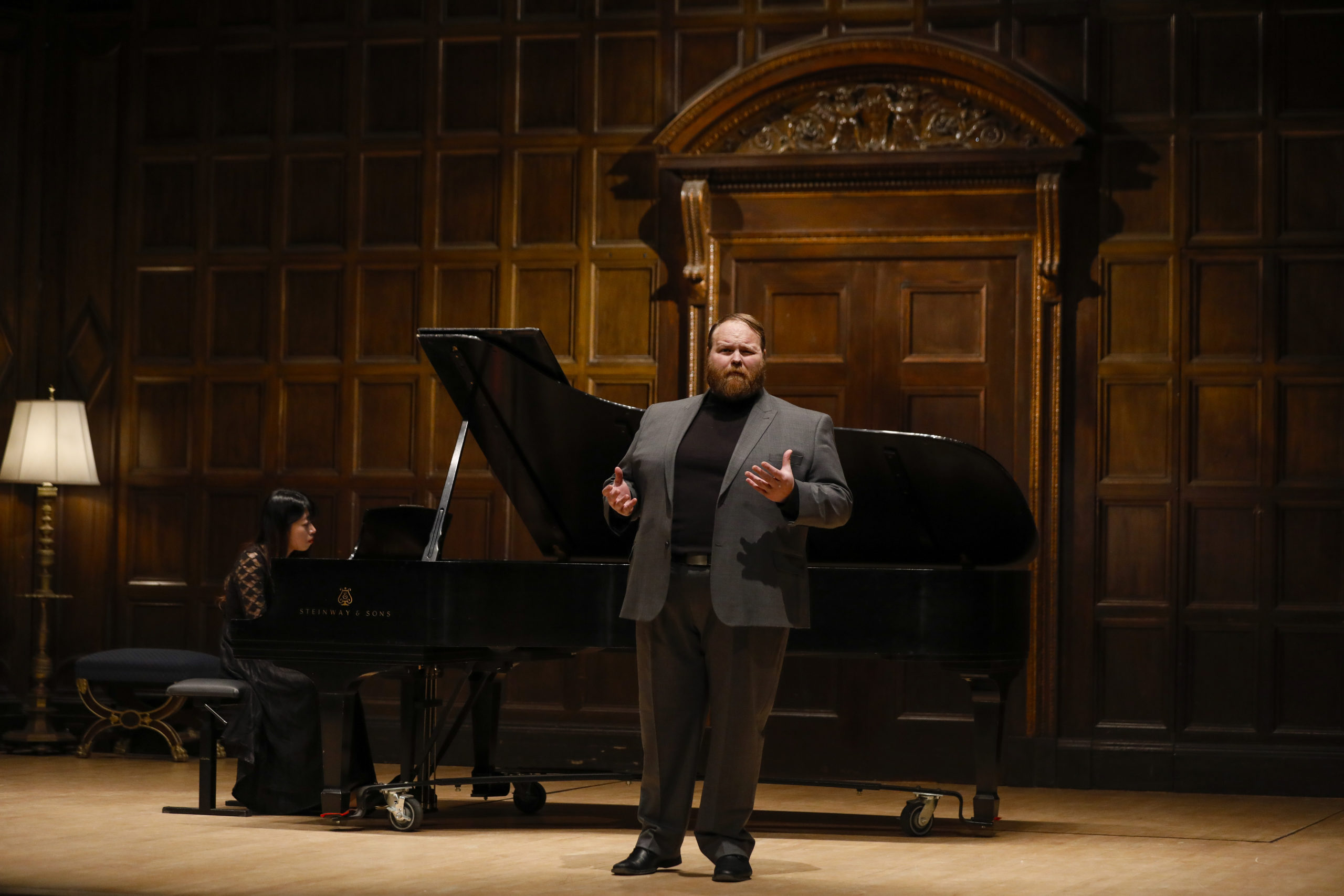 A man on stage in Kilbourn Hall singing with accompanying piano for the Friends of Eastman Opera competition