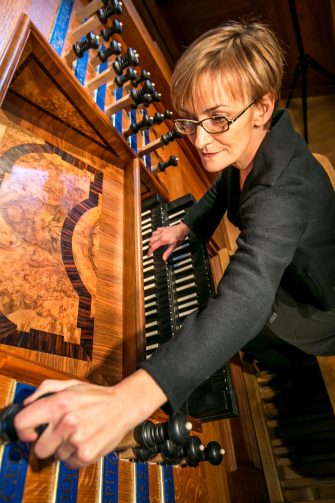Organist Annette Richards adjusting controls knob on the Italian Baroque Organ
